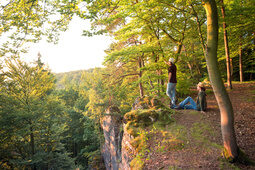 Zwei Personen sitzen am Rand eines Abhangs und schauen über den Oberpfälzer Wald