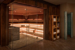 Neben der modernen Biosauna steht ein Holzregal, welches unter anderem Handtücher zur Verfügung stellt