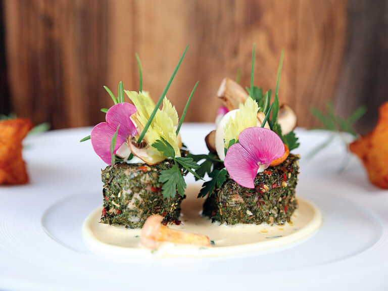 Auf einem Teller ist ein Gericht perfekt angerichtet und serviert.