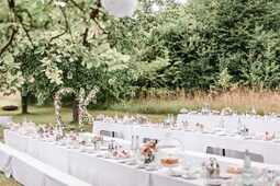 Auf einer Wiese wurden Tische zu Hochzeitstafeln zusammengestellt und schön dekoriert.