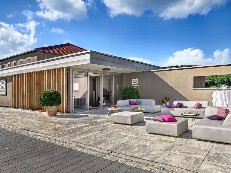 Vor dem Eingang sind Terrassenmöbel aufgestellt um die Sonne zu genießen