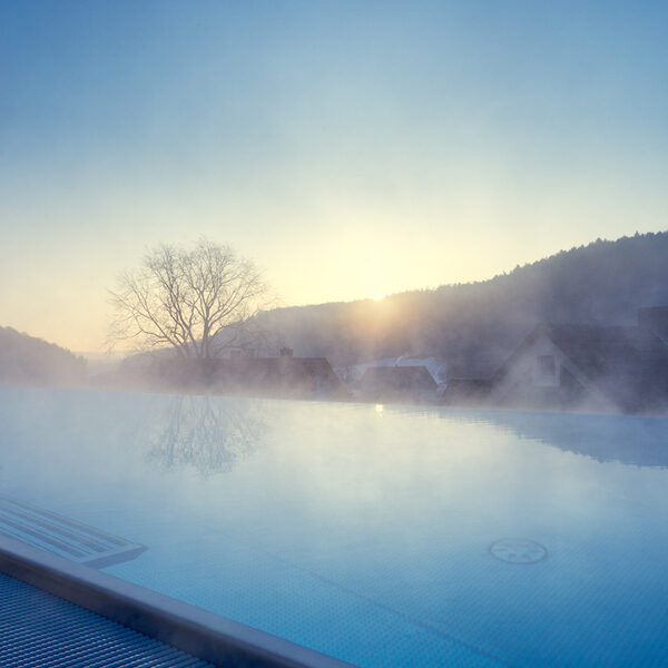 Der gro&szlig;e Skypool im Wellnesshotel dampft an einem kalten Wintermorgen