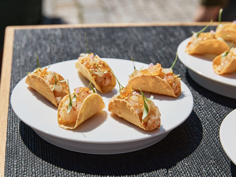 Kleine Tacos auf weißen Tellern an einem Tisch