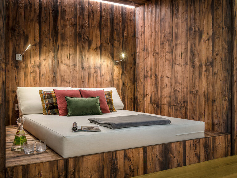 Ein Daybed ist in eine Nische in der Wand eingelassen und schafft durch die dunklen Holzwände eine beruhigende Atmosphäre.