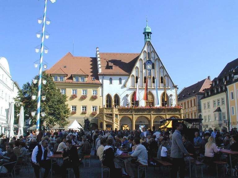 Auf dem amberger Rathausplatz sitzen Leute bei einem Fest