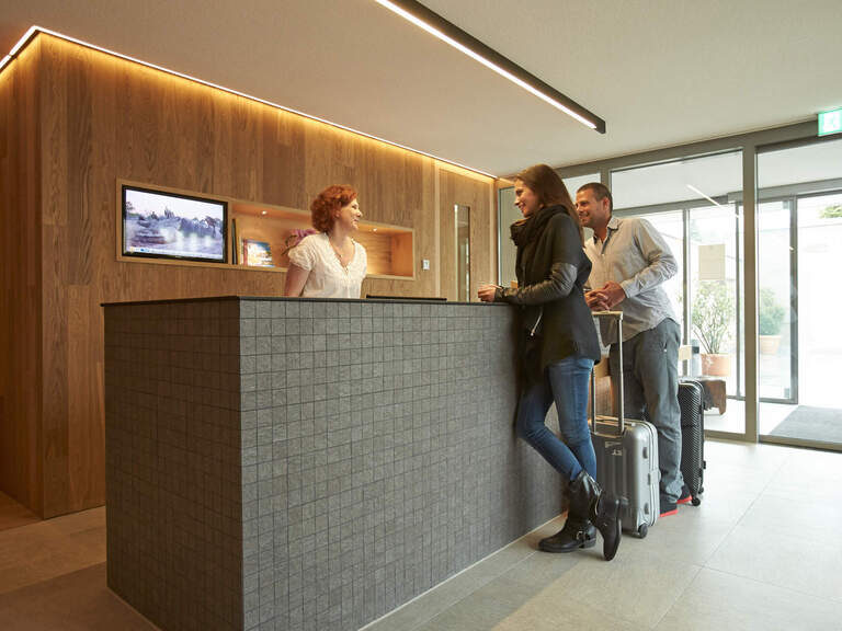 Eine Paar checkt in das Wellnesshotel ein.