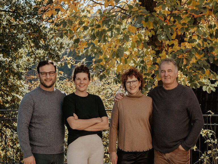 Die Gastgeberfamilie des Wellnesshotels steht lächelnd vor grünen Bäumen.
