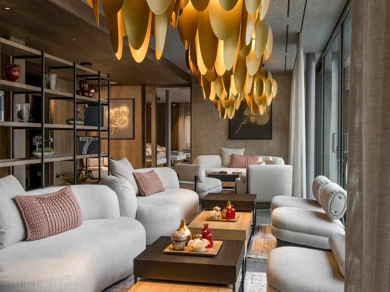 Ein gemütlicher Aufenthaltsbereich mit weichen Sofas und einer Designerlampe an der Decke.
