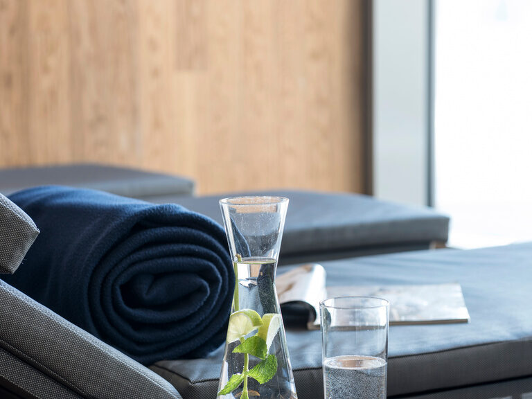 Ein Glas Wasser steht auf einem Beistelltisch im Ruhebereich des Wellnesshotels in der Nähe von Nünberg.