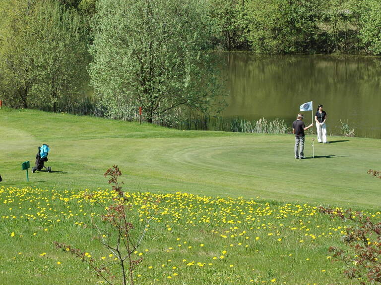 Golfspieler genießen einen Sommertag auf einem großen Golfgelände an einem See