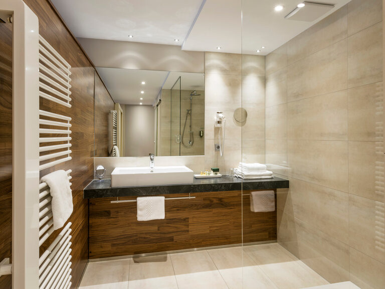Das harmonisch gestaltete Badezimmer im Grand-Deluxe Zimmer mit eleganten Kacheln und einem modernen Waschbecken.