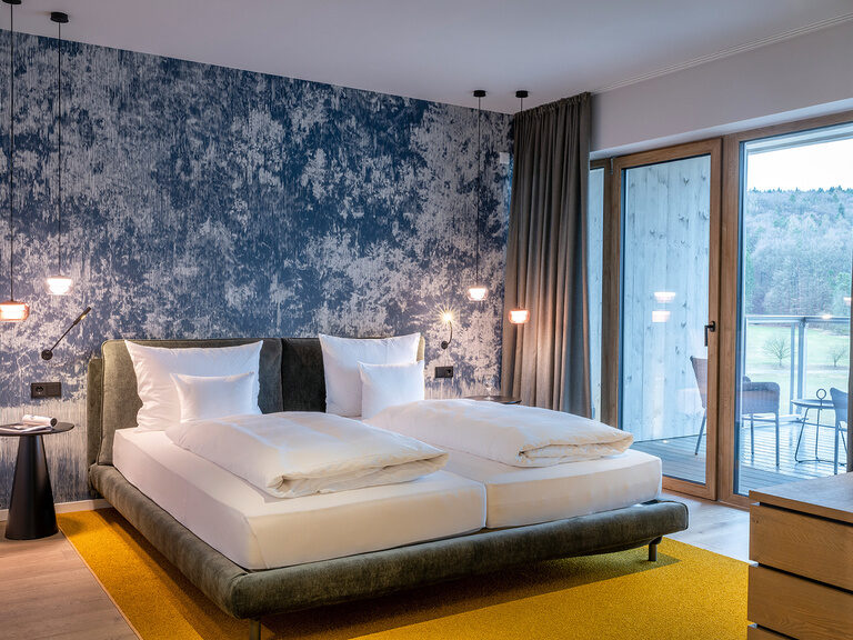 Das Bett nahe dem Fenster im Premium Zimmer bietet eine schöne Sicht über die Landschaft des Oberpfälzer Waldes.