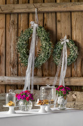 An der Tür der Scheune hängen für die Hochzeit Blumenkränze