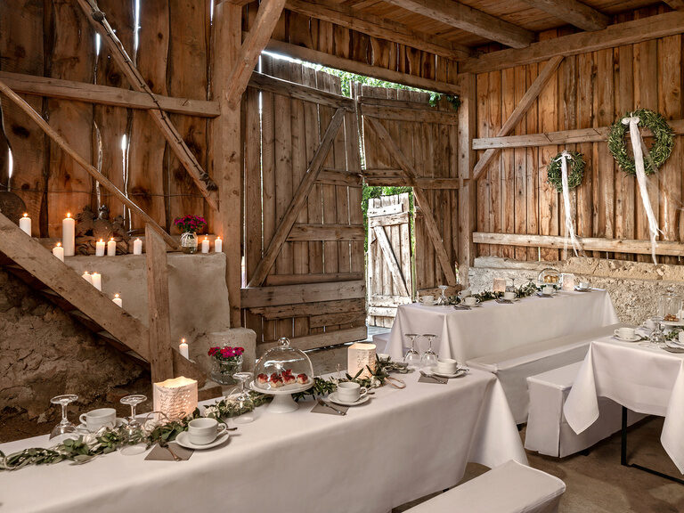 Die Scheune ist für die Hochzeit eingerichtet und dekoriert und es stehen bereits Kaffeetassen auf den Tischen.