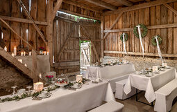 Die Scheune ist für die Hochzeit eingerichtet und dekoriert und es stehen bereits Kaffeetassen auf den Tischen.