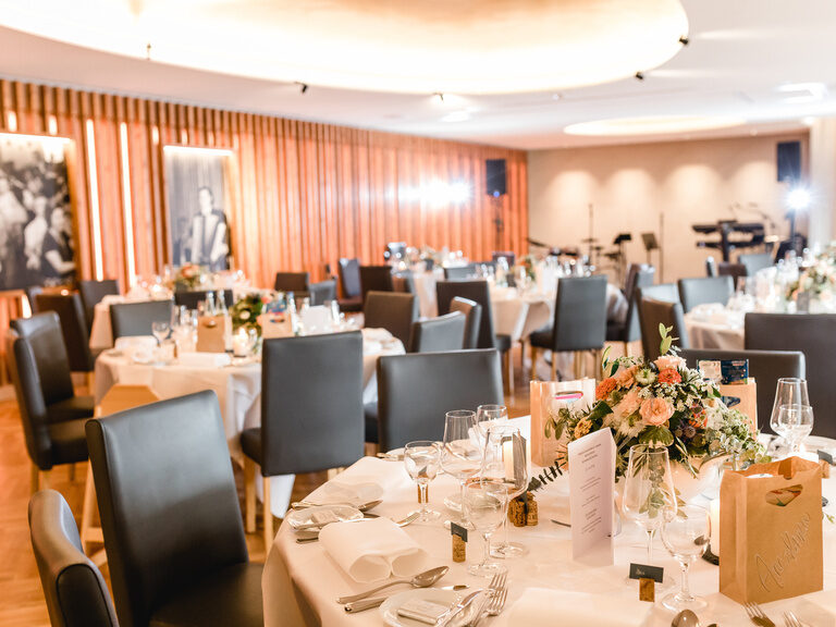 In dem großen Saal sind runde Tische für eine Hochzeit in der Oberpfalz gedeckt