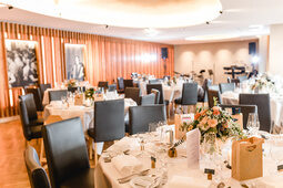 In dem großen Saal sind runde Tische für eine Hochzeit in der Oberpfalz gedeckt