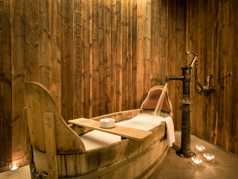 Der Hofpenzuber des Wellnesshotels ist in einem rustikal wirkenden Raum aufgestellt und wird durch Kerzen beleuchtet