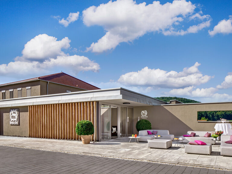 Der Eingangsbereich des Wellnesshotels ist mit Sitzgelegenheiten in der Sonne ausgestattet