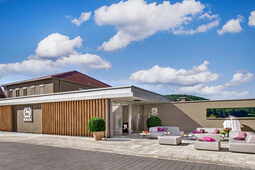 Der Eingangsbereich des Wellnesshotels ist mit Sitzgelegenheiten in der Sonne ausgestattet