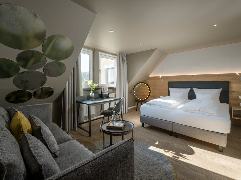 Ein dachgeschossiges Superior Zimmer mit einem Schreibtisch mit Ausblick über den Oberpfälzer Wald