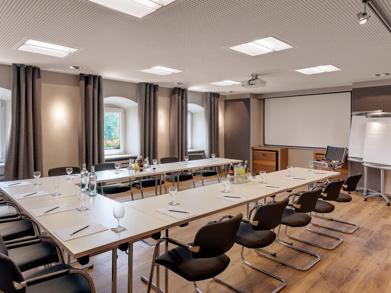 In einem Konferenzsaal wurden Tisch zu einer U-Form zusammengeschoben.