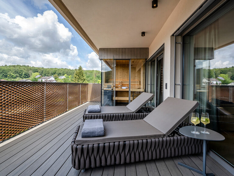 Zwei Liegen stehen auf der großen Terrasse der Spa Suite Deluxe vor der Sauna