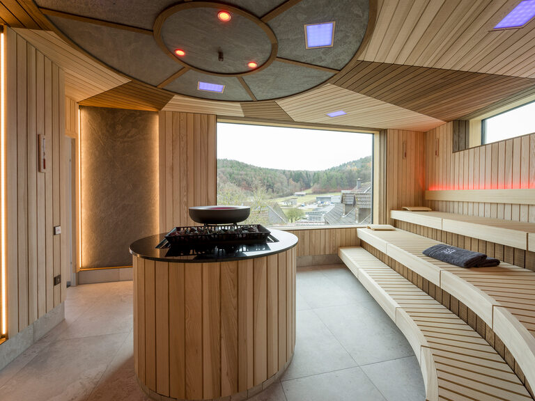 Eine elegant gestaltete Sauna mit großen Fenstern und Holzverkleidung.
