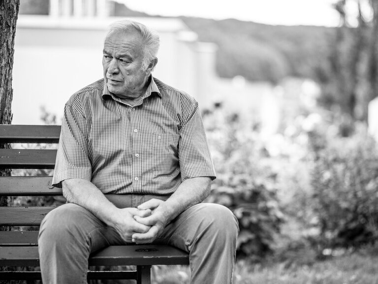 Der Herr auf dem Schwarz-Weiß Portrait sitzt auf einer Bank