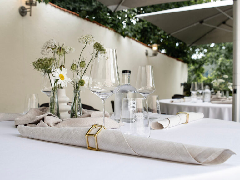 Ein weißer Tisch ist bereits mit Gläsern und Servietten ausgestattet