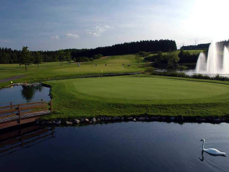 Ein See mit Springbrunnen neben einem Golfplatz