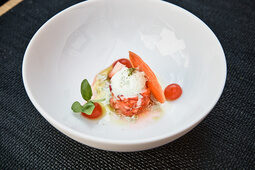 Ein Gericht, das mit Tomaten und grünen Blättern verziert ist, wartet darauf im Gourmetrestaurant Cheval Blance serviert zu werden