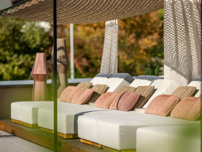 Die Poolterrasse des Wellnesshotels mit überdachten Holzliegen.